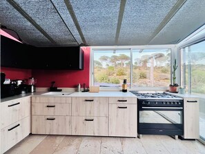 Een moderne keuken met een groot kookeiland, inbouwapparatuur en uitzicht op de omgeving.