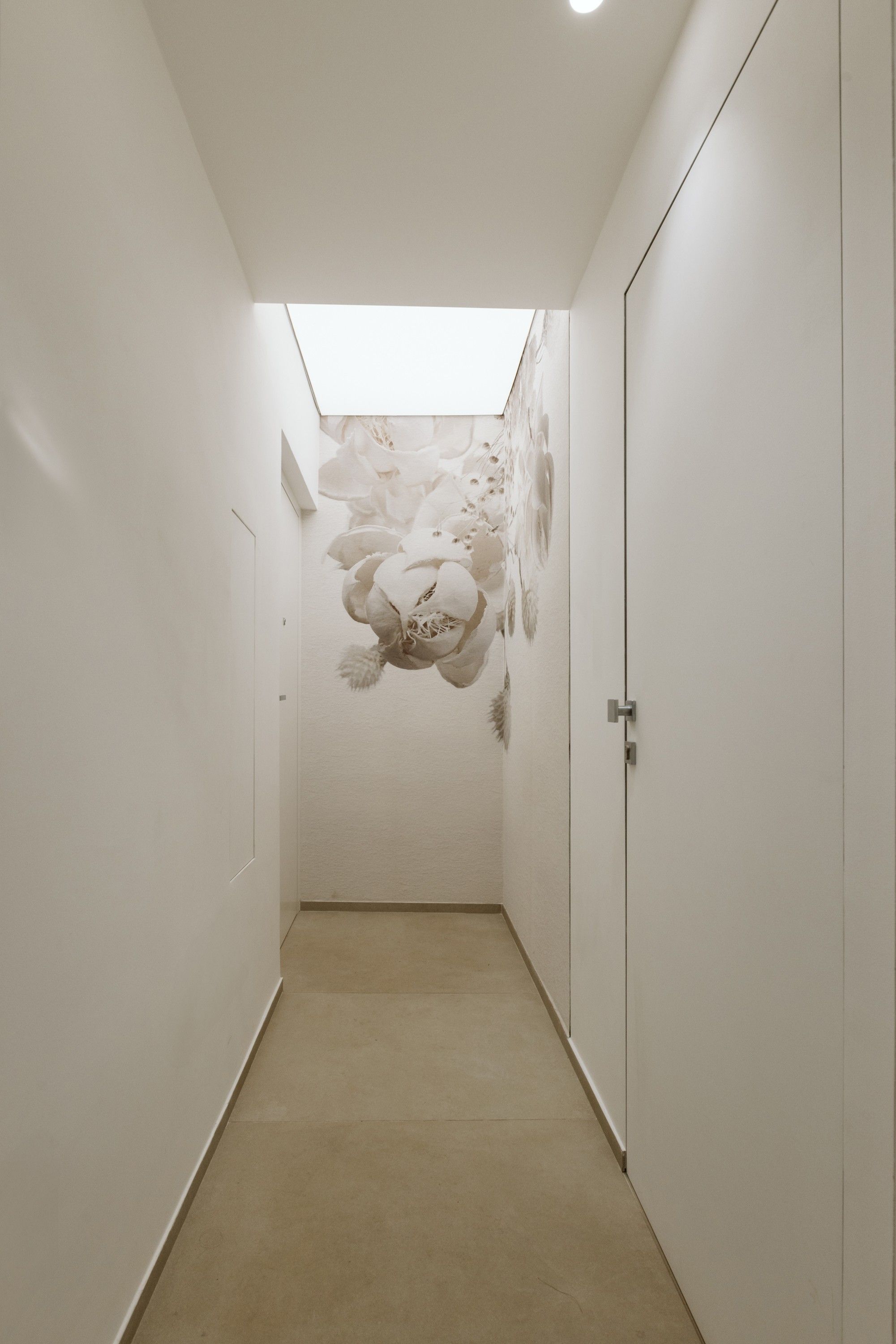 Un couloir étroit avec une lucarne et une peinture murale.