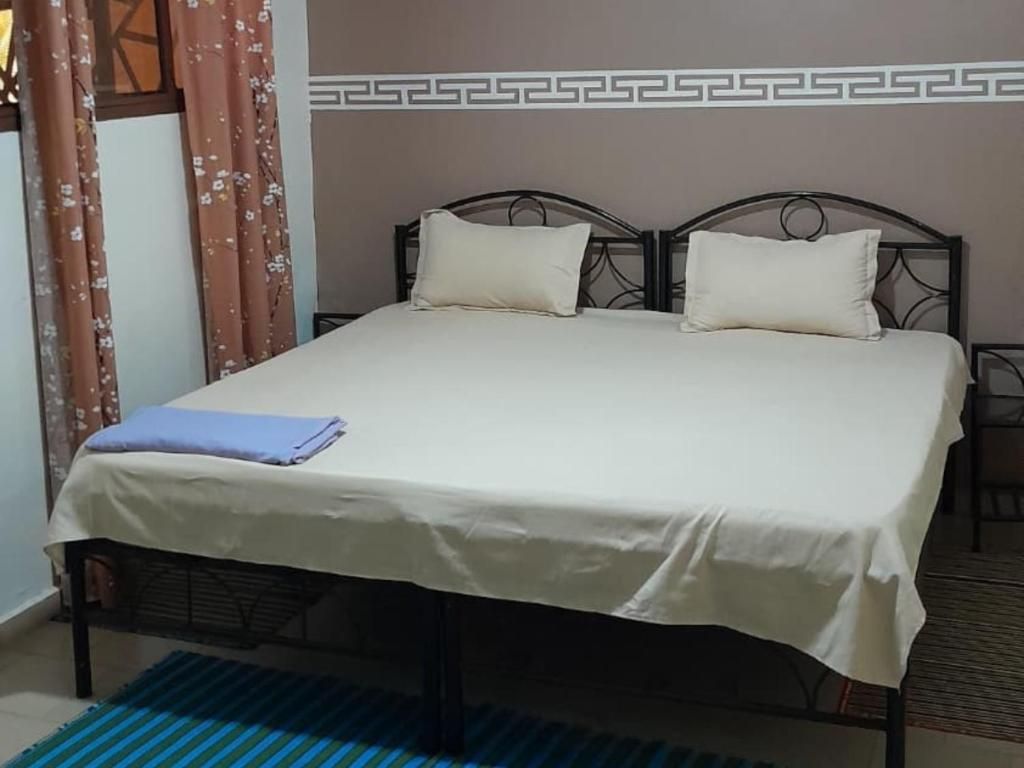A bed with a white bedspread, two pillows, and a folded blue blanket.