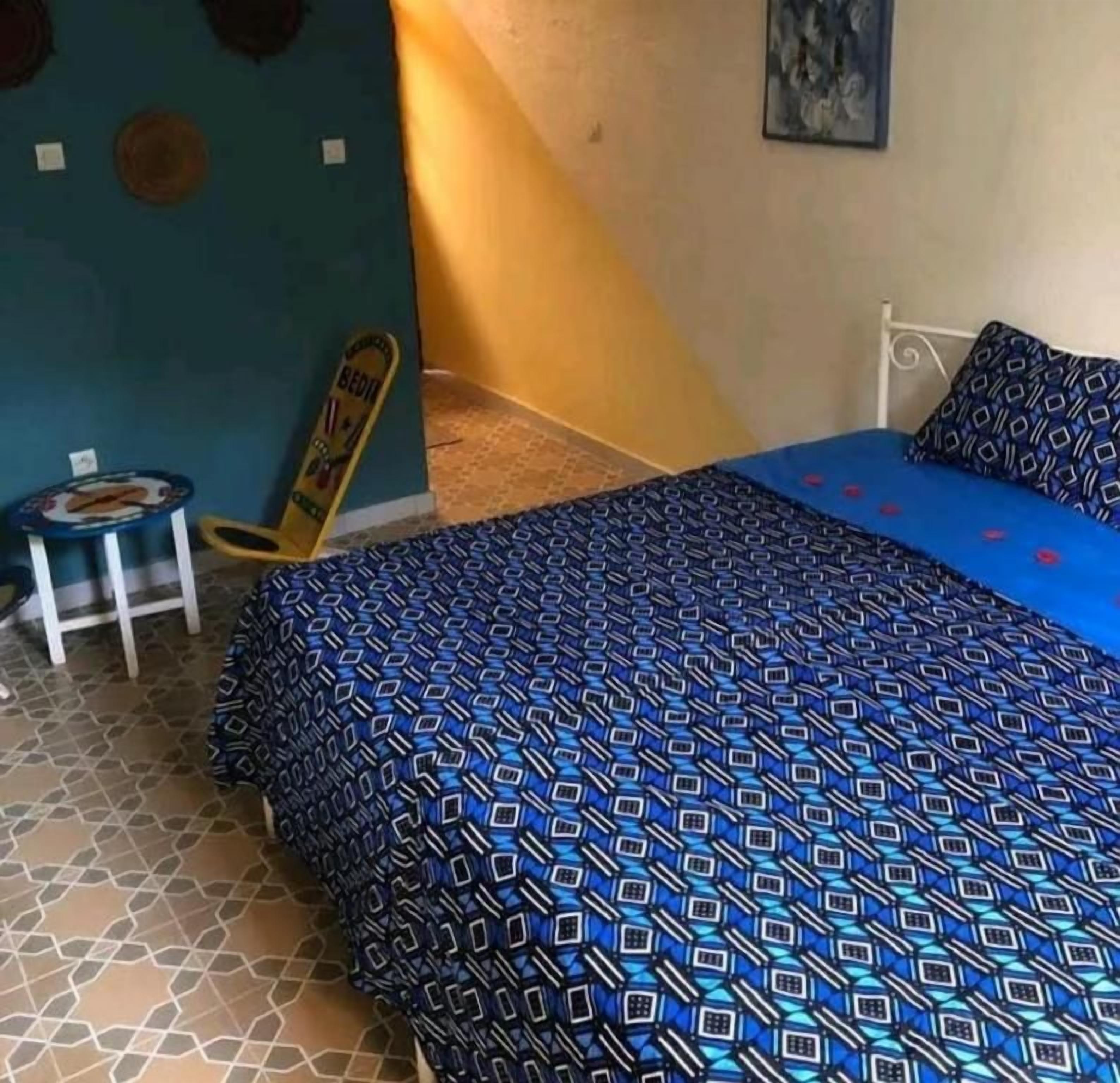 A bedroom with a bed, a chair, and a small table.