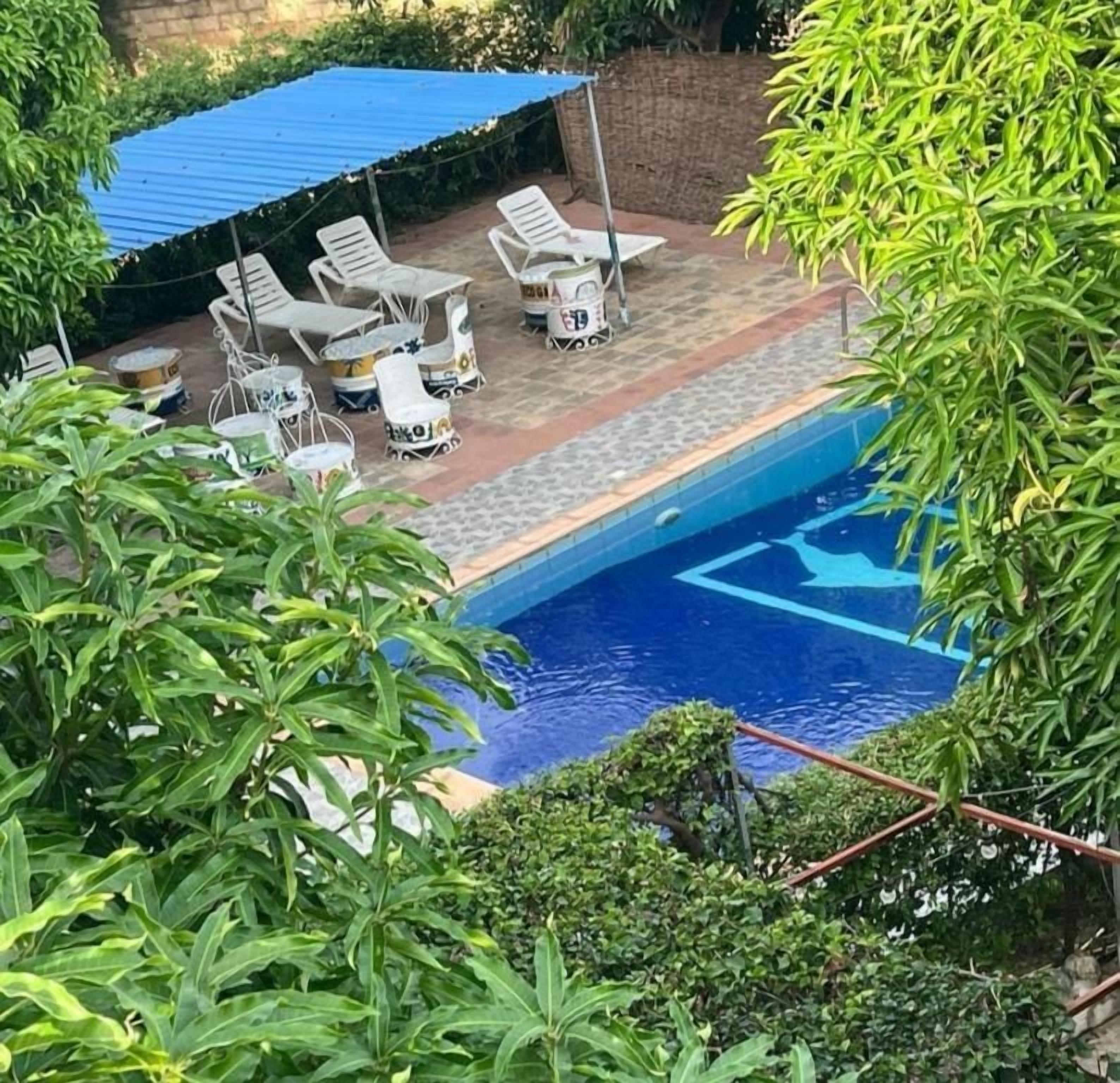A swimming pool with lounge chairs and a covered area.