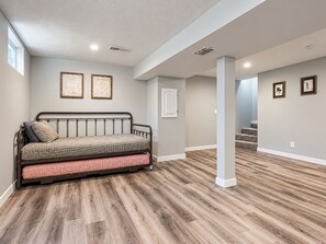 A room with a bed, a door, and a staircase. - Amber & Oak - Theater & Fire Pit (Omaha)