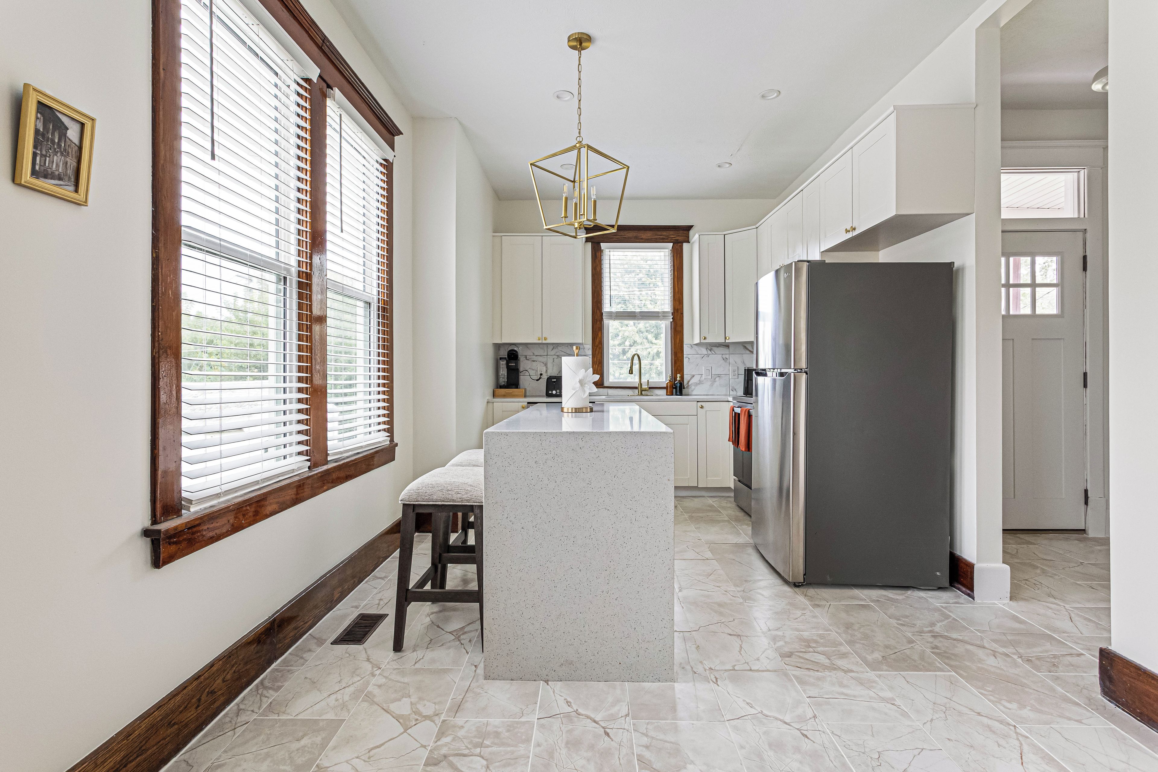 A kitchen with a central island, white cabinetry, and a stainless steel refrigerator.