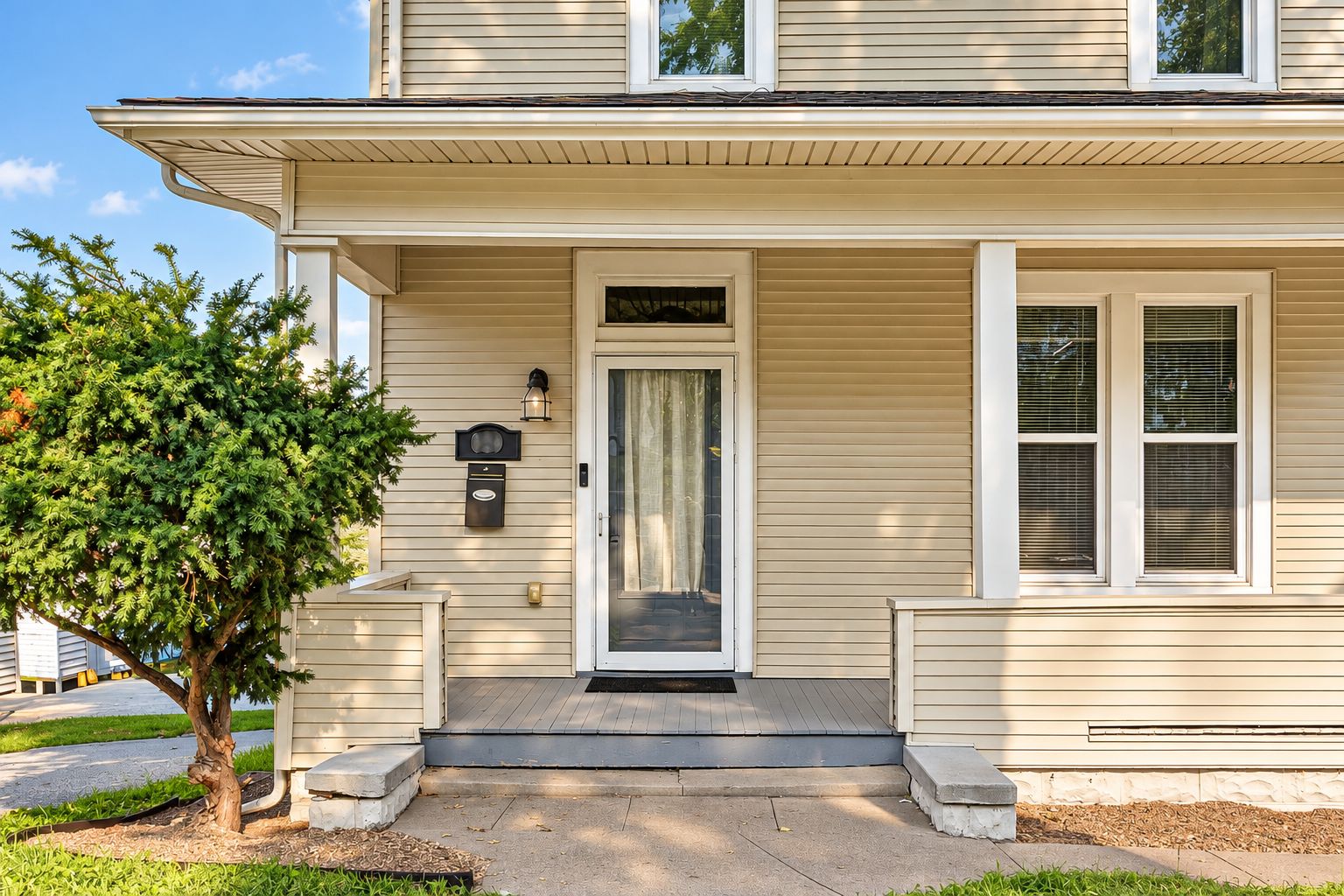 Welcoming front porch and entry framed by mature landscaping.