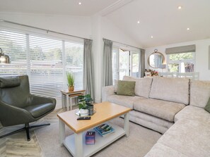 A modern living room with a leather chair, a beige sofa, a wooden coffee table, and a potted plant. - Thirlmere Scar (Windermere)