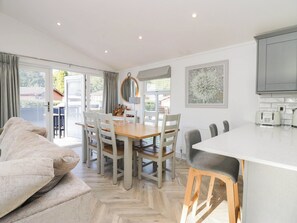 A modern kitchen with a central island, dining area with chairs, and a sofa. - Thirlmere Scar (Windermere)