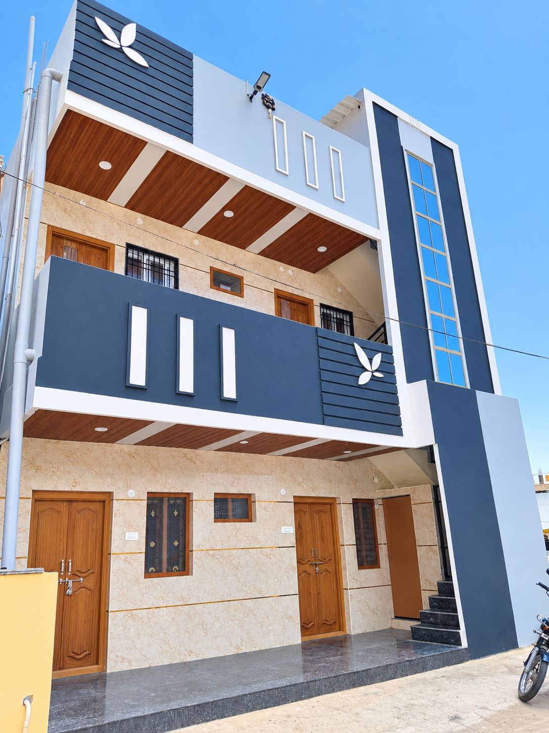 Un edificio moderno de dos pisos con un balcón, varias puertas y una escalera que conduce al nivel superior.