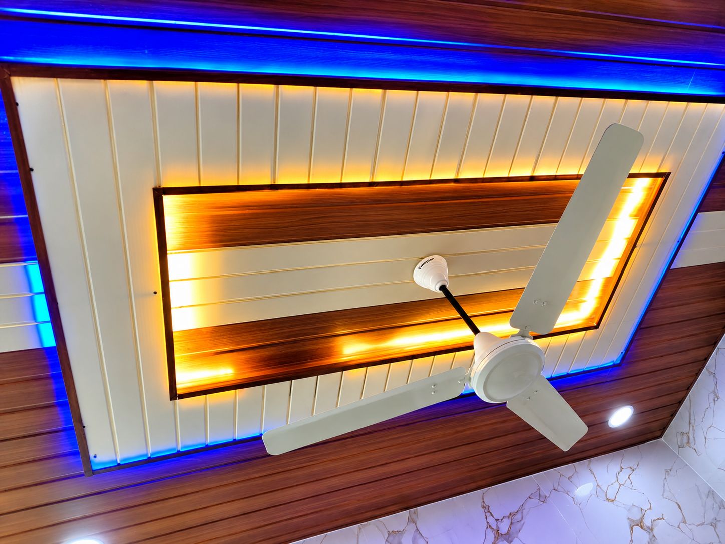 Techo con paneles de madera, iluminación empotrada y un ventilador.