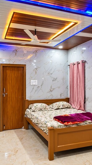 A bedroom with a bed, wooden door, marble-patterned walls, and a ceiling with recessed lighting.