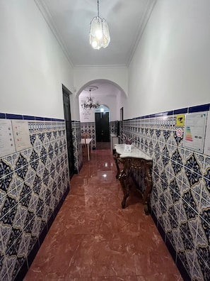A hallway with patterned tiles, a chandelier, and a door with a sign.