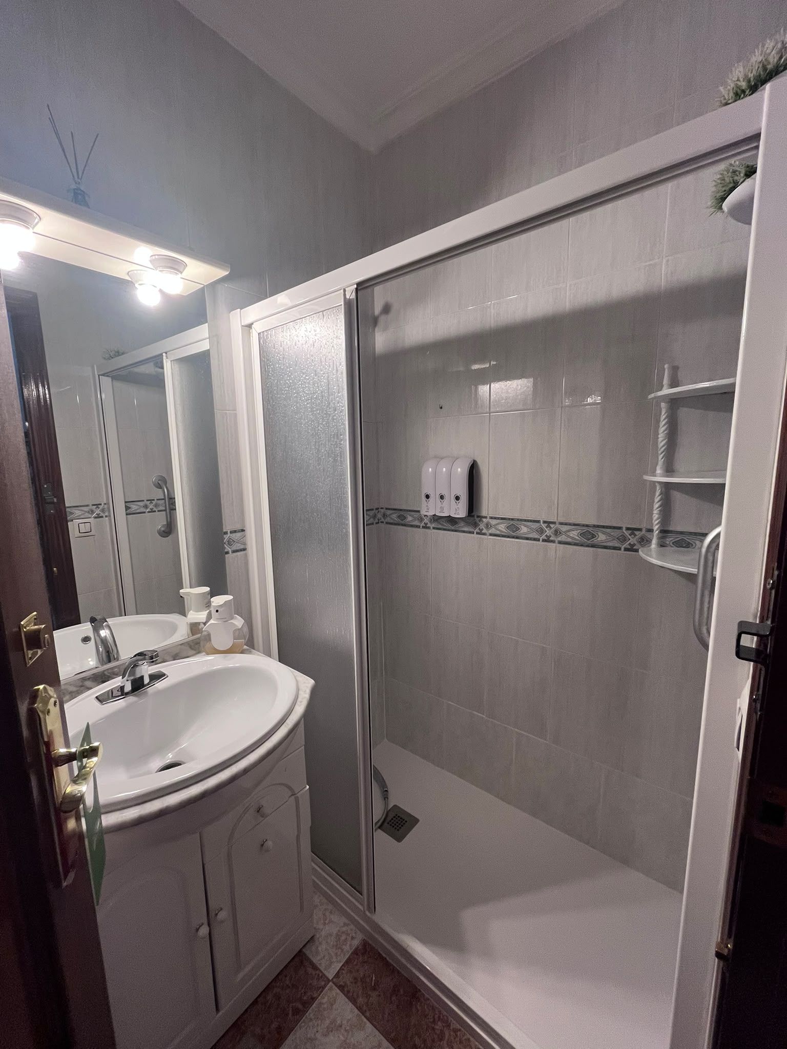 A bathroom with a white sink, mirror, and a glass-enclosed shower.