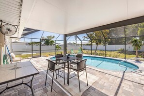 An outdoor patio with a pool, a table, and chairs. - Free Heated Pool Home, Luxury Beds, Pet Friendly (Cape Coral)