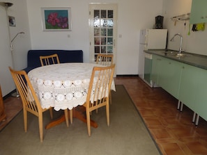 A dining area with a round table covered in a white lace tablecloth, surrounded by wooden chairs. - In the heart of the Luberon Nature Park, in Rustrel: a quiet vacation rental perfect for relaxing (Rustrel)