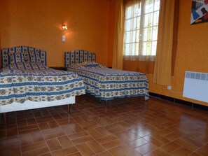 A room with two beds, a window with curtains, a wall-mounted light, and a radiator. - In the heart of the Luberon Nature Park, in Rustrel: a quiet vacation rental perfect for relaxing (Rustrel)