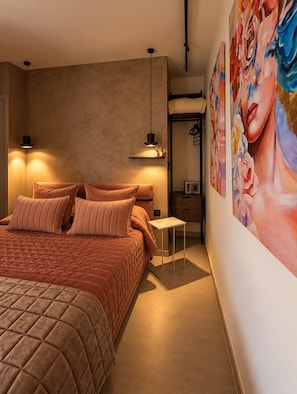 Ein Schlafzimmer mit einem großen Bett, Nachttischlampen, einem Nachttisch und einer Wand mit einem floralen Gemälde.