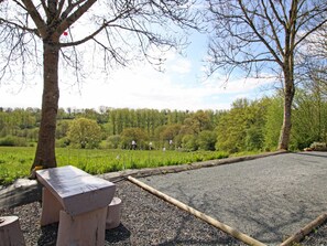 Ein Picknickplatz mit einer Bank und einem Tisch, umgeben von einem Kiesweg und einer Wiese mit Bäumen im Hintergrund.