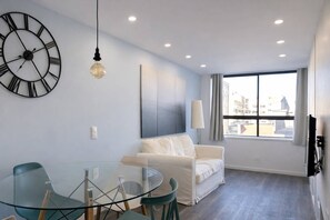 A modern living room with a glass table, white sofa, and a large wall clock. - Downtown Porto. Trindade Metro. (Porto)
