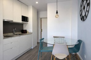 A modern kitchen with white cabinets, a microwave, and a granite countertop. There is a glass dining table with teal chairs. - Downtown Porto. Trindade Metro. (Porto)