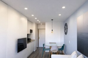 A modern kitchen with a flat-screen TV, a dining area with a glass table and chairs, and a ceiling with recessed lighting. - Downtown Porto. Trindade Metro. (Porto)