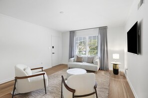 A modern living room with a sofa, two armchairs, a coffee table, a TV, and a lamp. - Historic Savannah Retreat w Modern Comforts (Savannah)