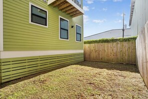 Una casa verde con terraza de madera y patio cercado.