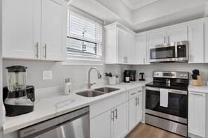 A modern kitchen with white cabinetry, stainless steel appliances, and a dishwasher. - Renovated Home 3BA Near French Quarter & Superdome (New Orleans)