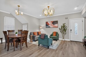 A dining area with a wooden table and chairs, a gray sofa, and a teal armchair. - Renovated Home 3BA Near French Quarter & Superdome (New Orleans)