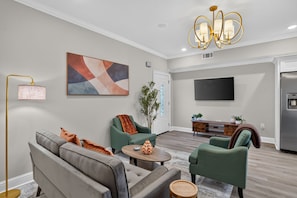 A modern living room with a sofa set, a coffee table, and a television mounted on the wall. - Renovated Home 3BA Near French Quarter & Superdome (New Orleans)
