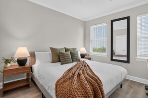 A bedroom with a bed, two bedside tables, lamps, a mirror, and a window with blinds. - Renovated Home 3BA Near French Quarter & Superdome (New Orleans)