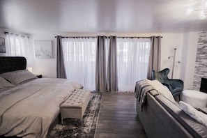 A bedroom with a large bed, a sofa, a chair, and a floor lamp. - Downtown Aspen with Patio, Fireplace, Parking, W/D (Aspen)