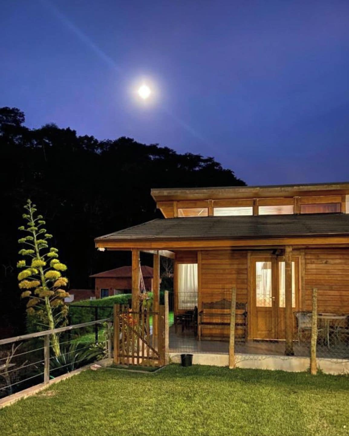 A wooden house with a covered porch and a garage, surrounded by a well-maintained lawn.