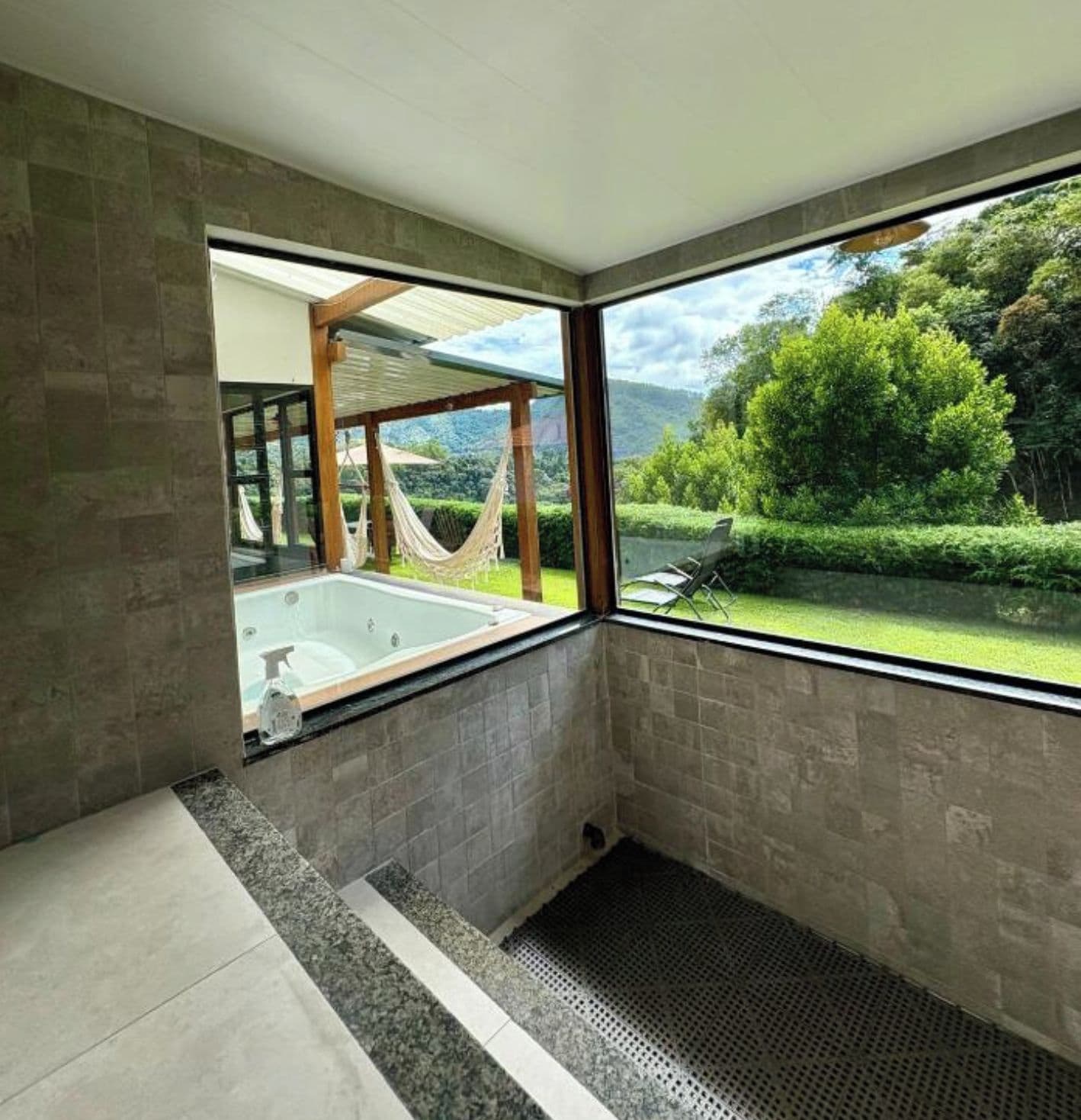 A modern bathroom with a large window, a bathtub, and a shower area.
