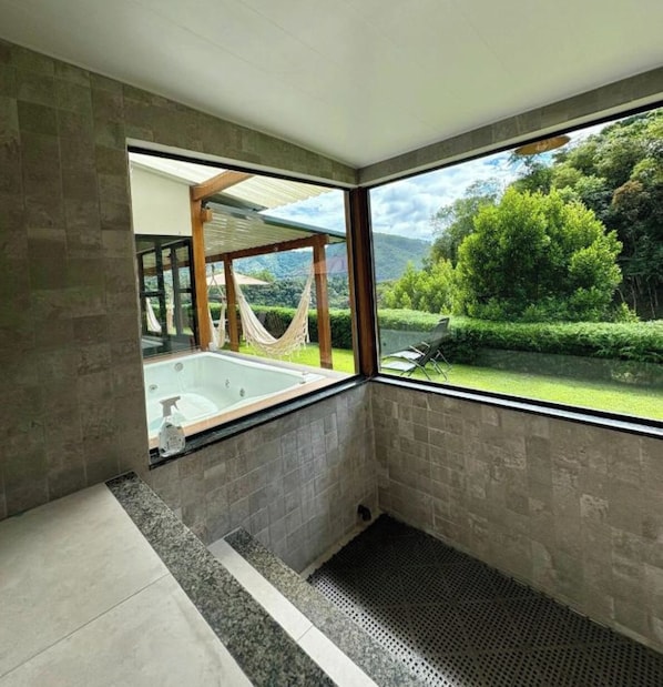 A modern bathroom with a large window, a bathtub, and a shower area.