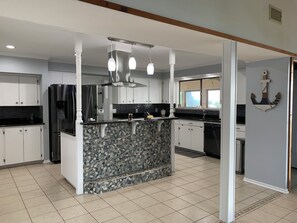 Een moderne keuken met een centraal eiland, witte kasten en een betegelde achterwand.
