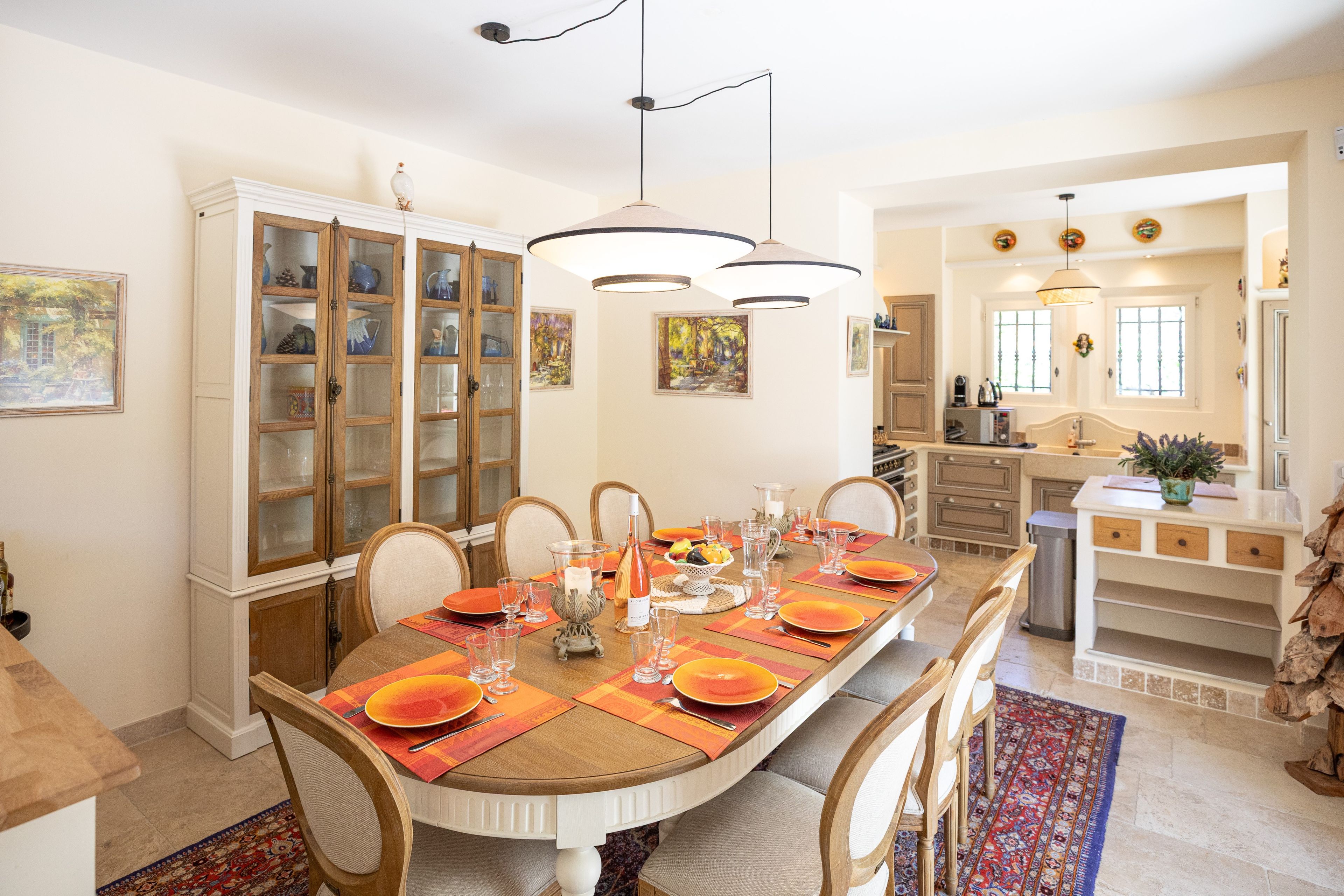 Un espace repas avec une longue table dressée pour six personnes, entourée de chaises en bois.