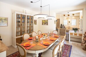 Un espace repas avec une longue table dressée pour six personnes, entourée de chaises en bois.