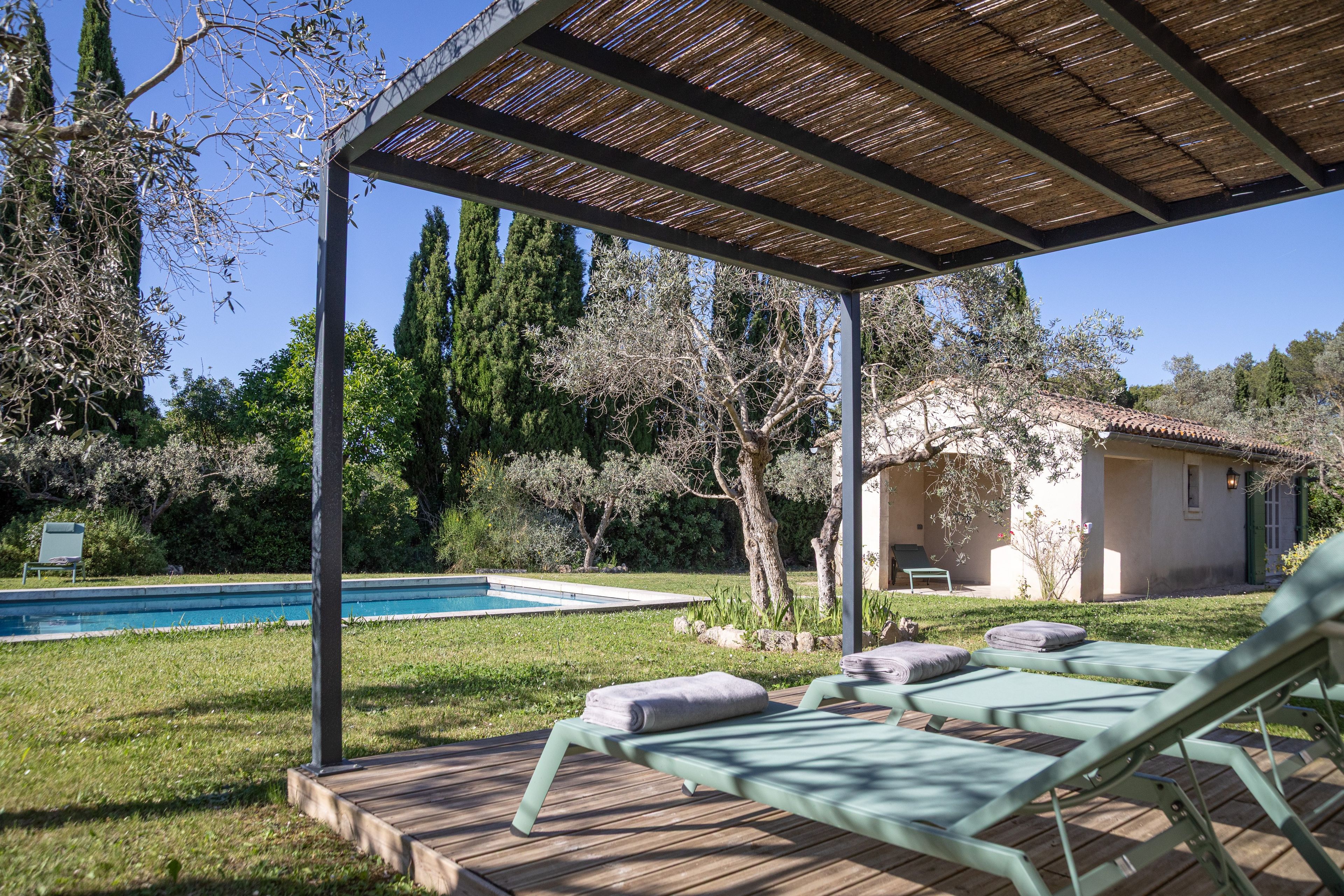 A poolside area with lounge chairs and a pergola.