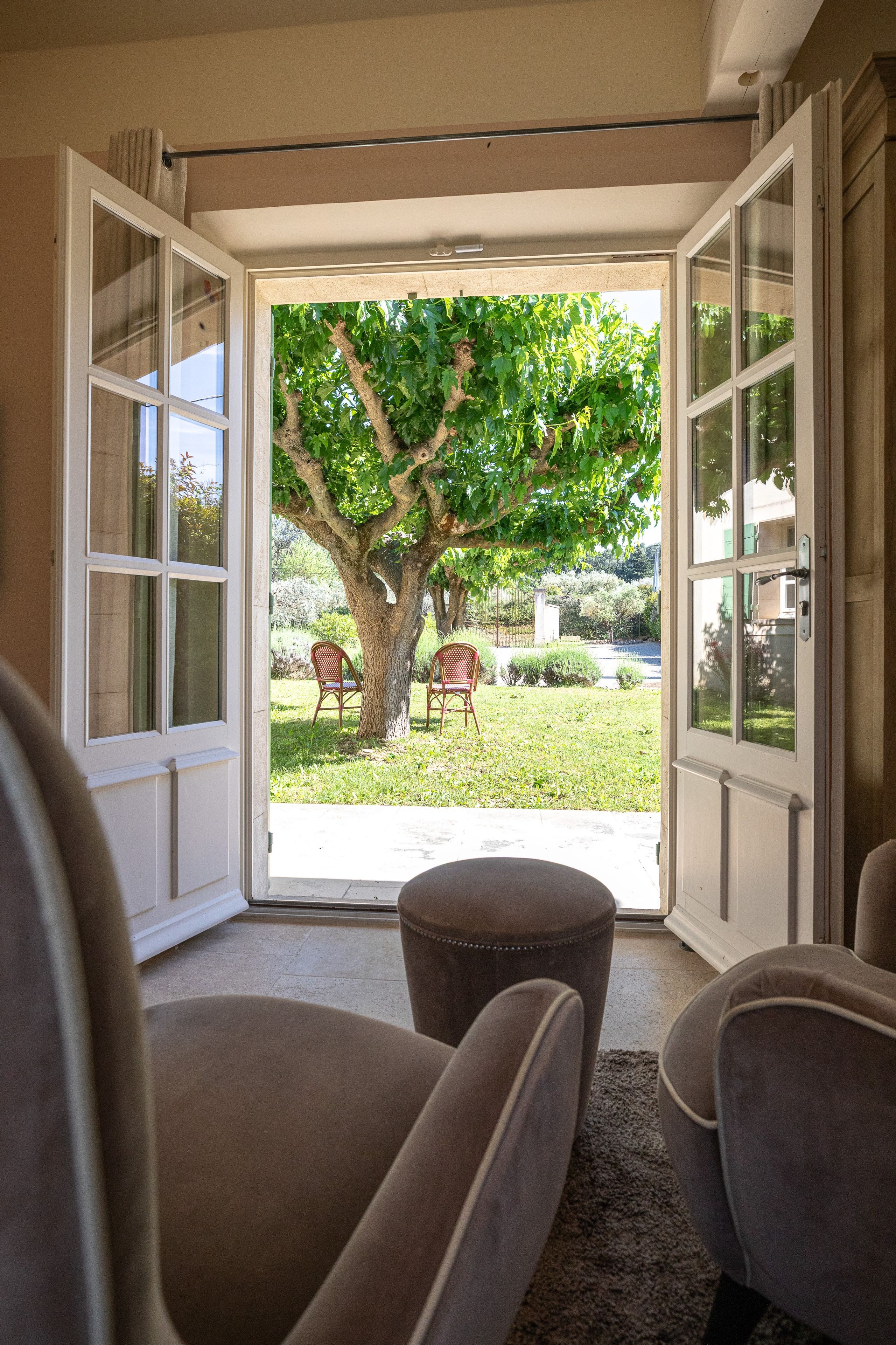 Eine offene Schiebetür, die auf eine Terrasse mit einem Baum und zwei Stühlen führt.