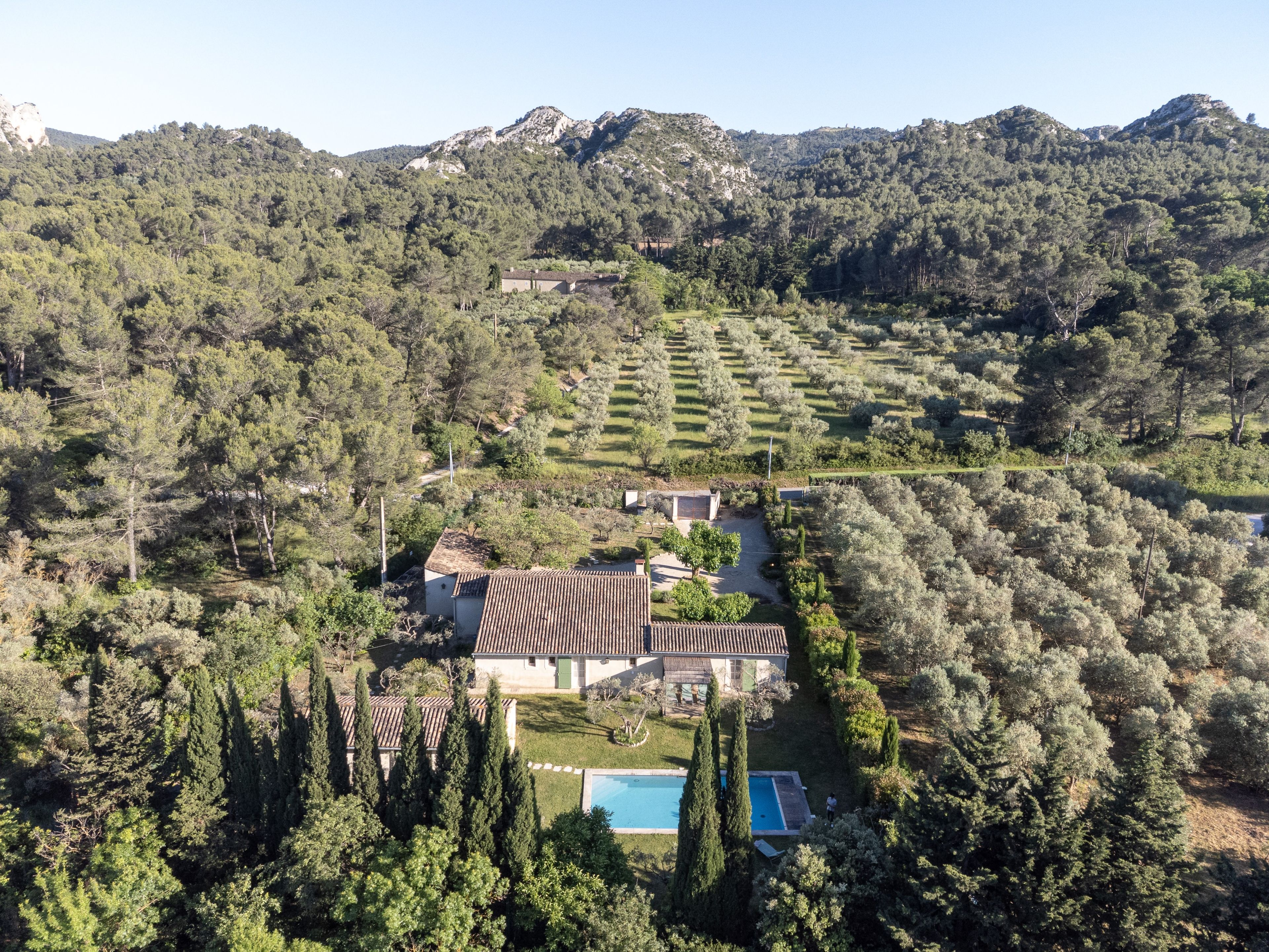 Une villa avec piscine, entourée d’une forêt dense et de montagnes.