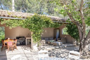 Eine Außenpatio mit Tisch und Stühlen, einer Sitzecke und einer mit Grünwerk belubten Pergola.