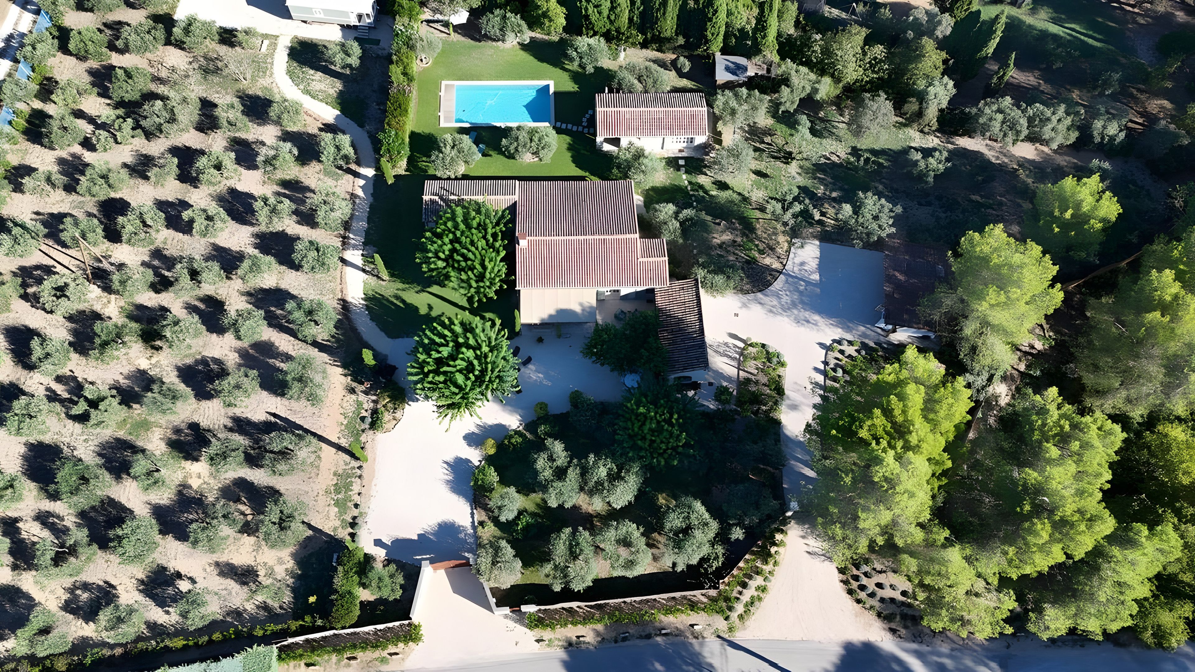 An aerial view of a property with a swimming pool, a patio area, and a garden.