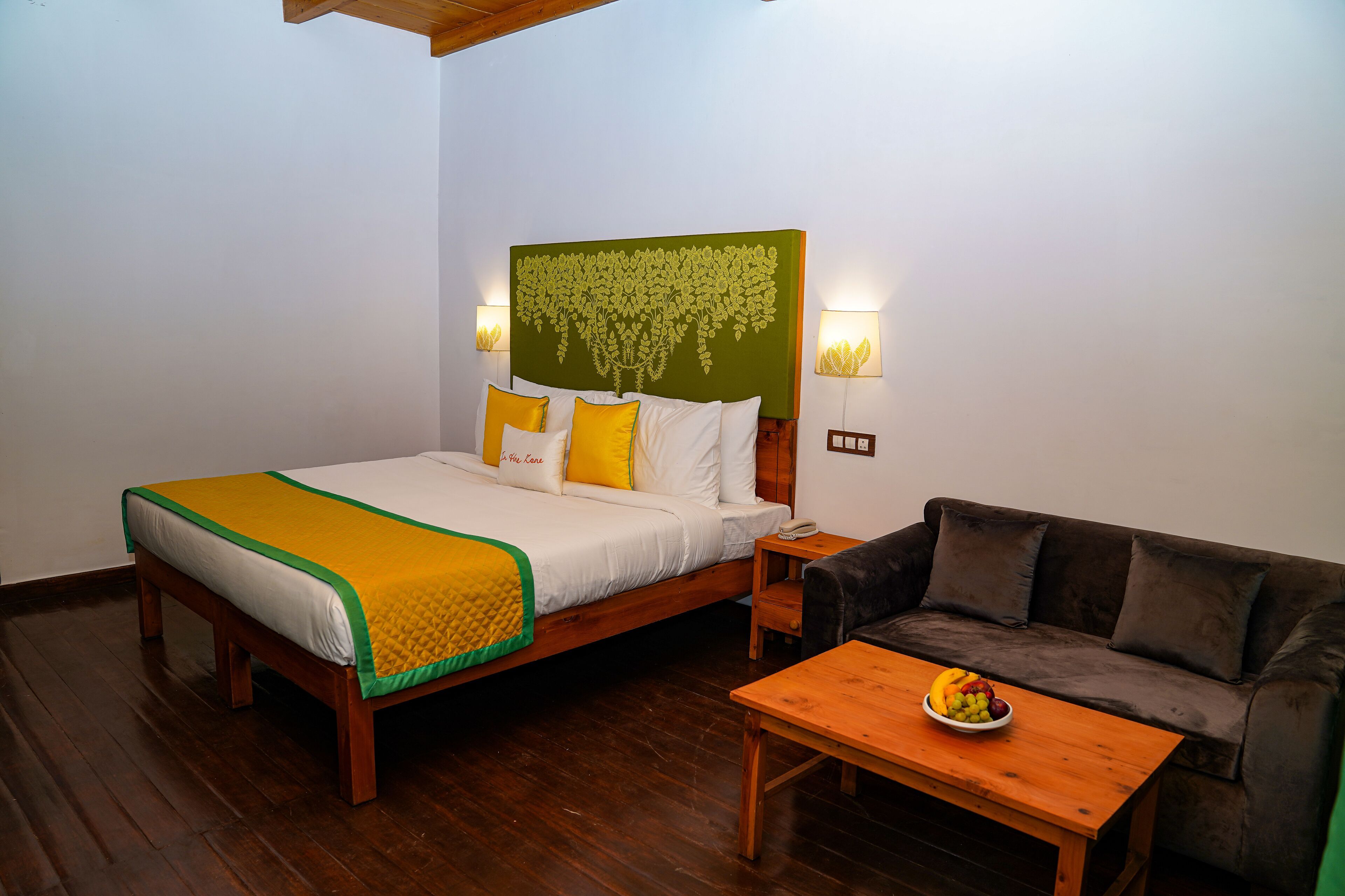 A bedroom with a bed, bedside tables, a couch, and a fruit bowl.