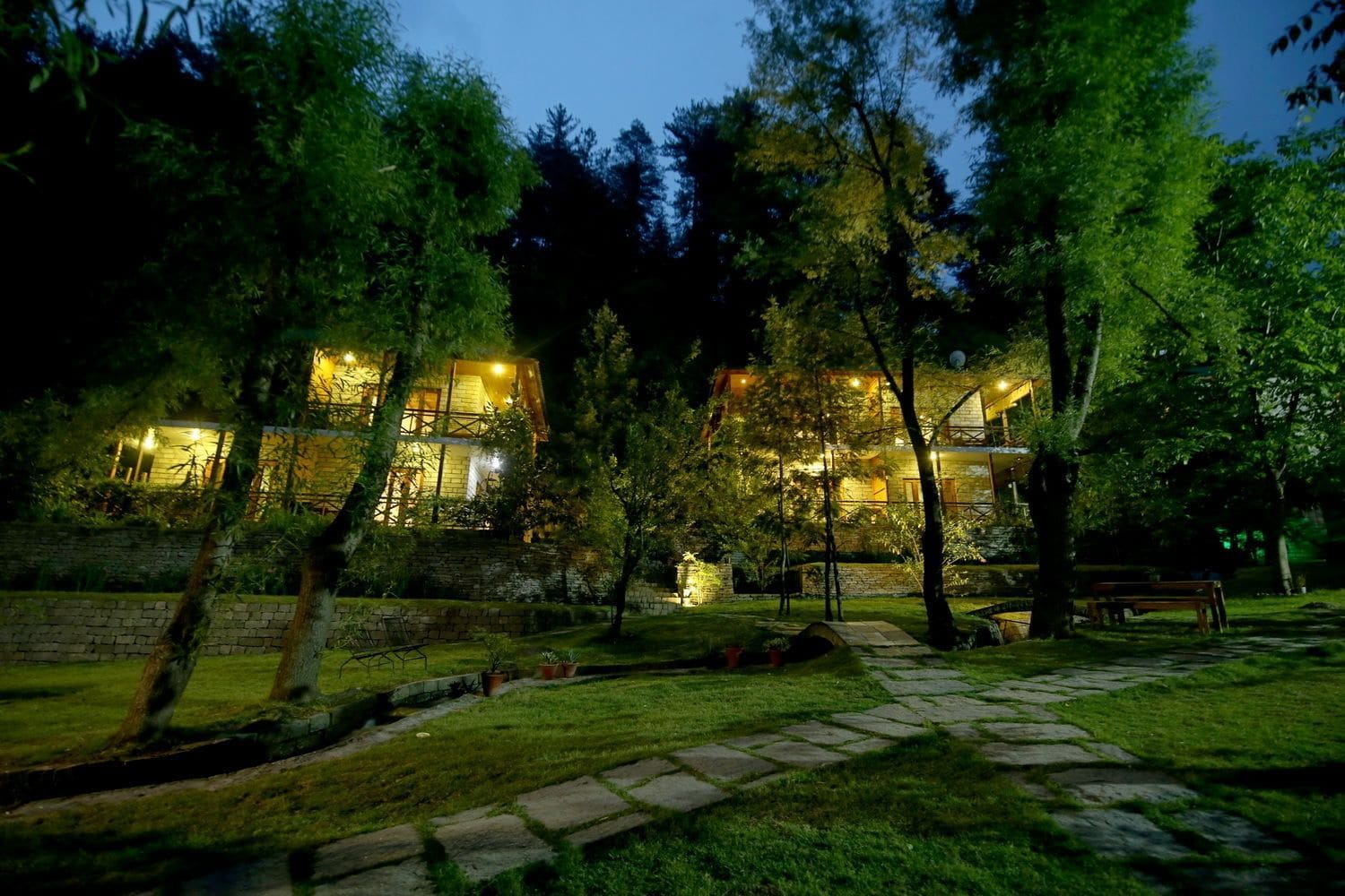 A multi-story building with a stone facade, surrounded by trees and a stone pathway.