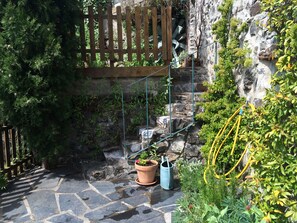 A stone pathway leading to a wooden gate, surrounded by lush greenery and a stone wall. - Holiday Home 'L'ecurie' with Mountain View (Vira)