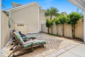 A covered patio area with lounge chairs and a small garden with palm trees. - Luxury 3BR 2.5BA Townhome w/Resort Perks (North Myrtle Beach)