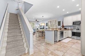 A kitchen with a central island, a dining area, and a staircase. - Luxury 3BR 2.5BA Townhome w/Resort Perks (North Myrtle Beach)