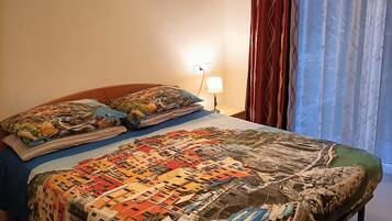 Ein Schlafzimmer mit einem großen Bett, einem Nachttisch mit Lampe und einem Fenster mit Vorhängen.