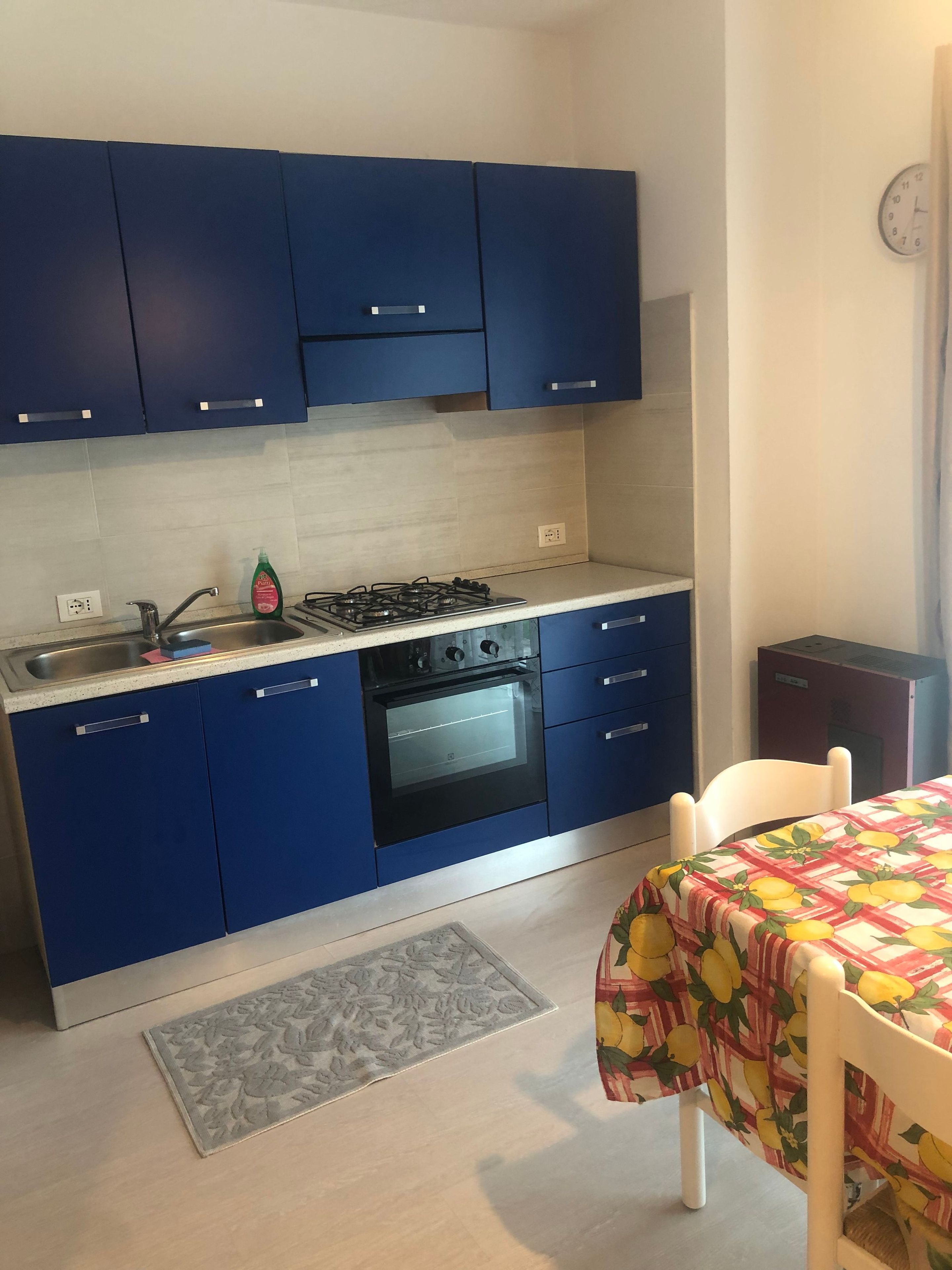Eine kleine Küche mit blauen Schränken, einem Gasherd, einem Backofen und einer Spüle.