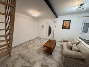 Una habitación con un banco de madera, un sofá, una puerta y una lámpara en el techo.