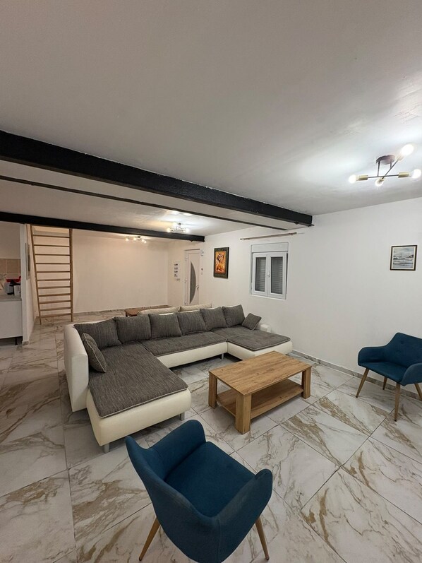 Un salon moderne avec un canapé d’angle, une table basse et deux fauteuils.